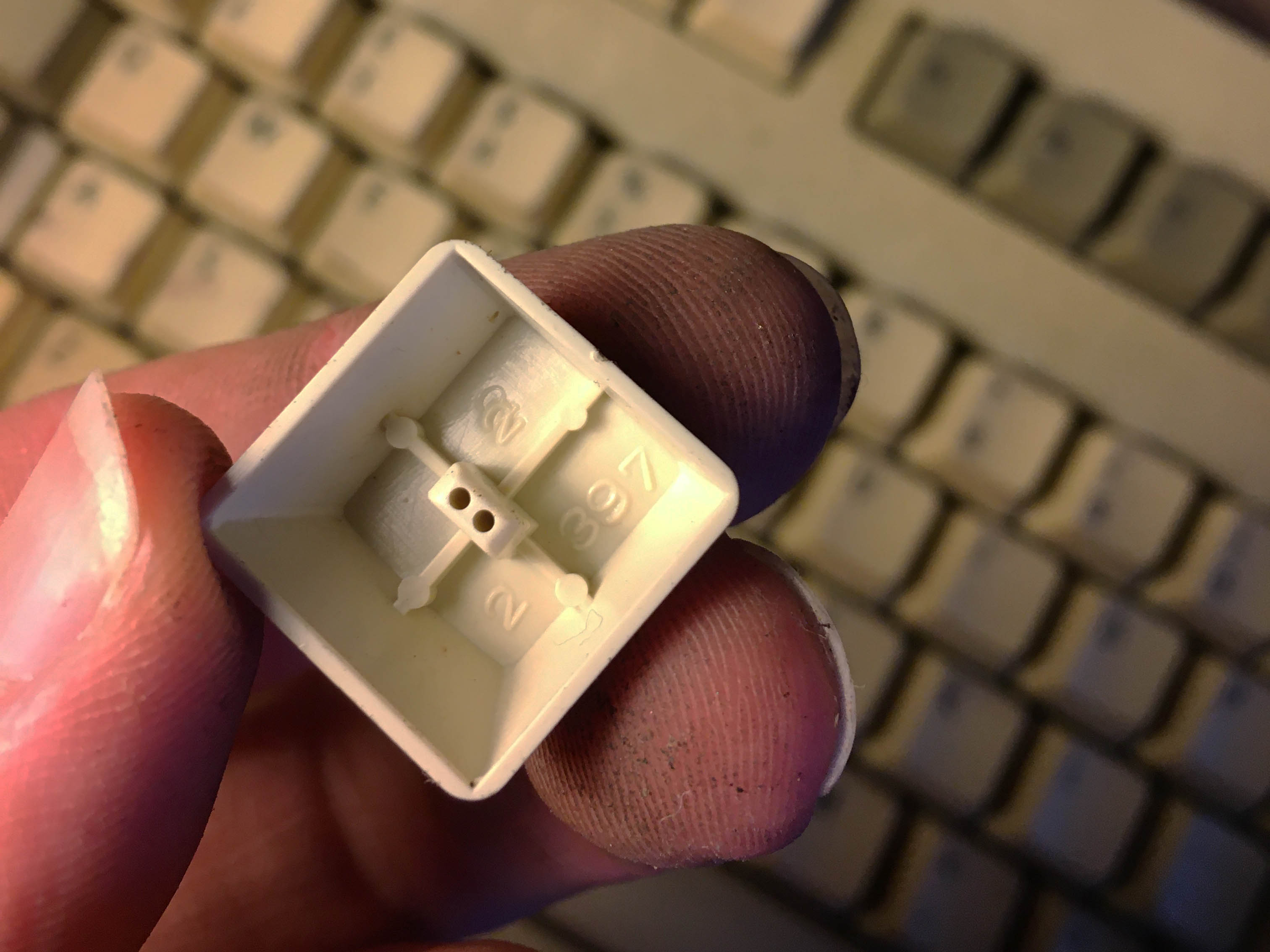 Photo of keycap being held upside-down of a 1U keycap.
