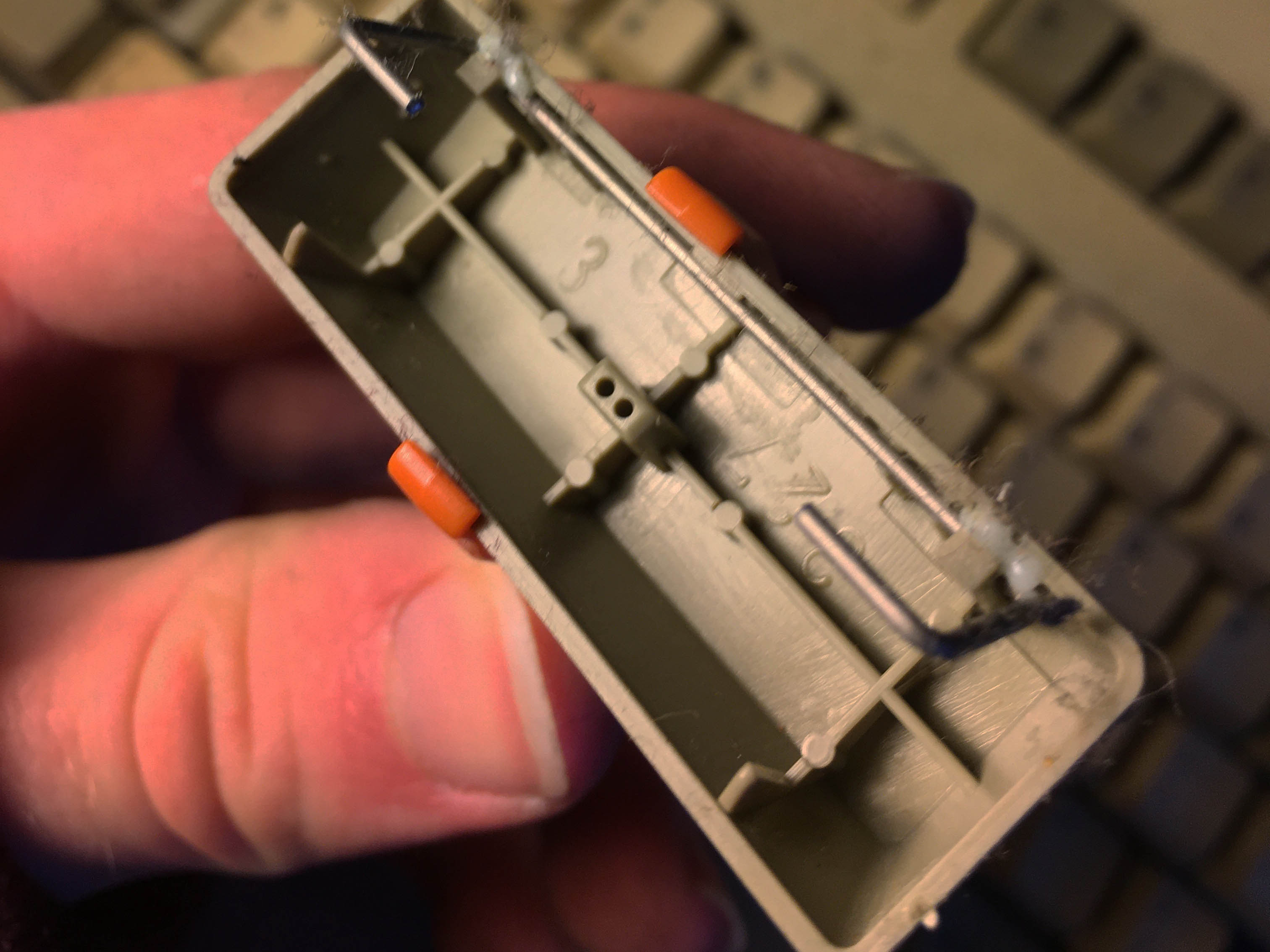 Photo of keycap being held upside-down of a longer keycap showing stabiliser bar.