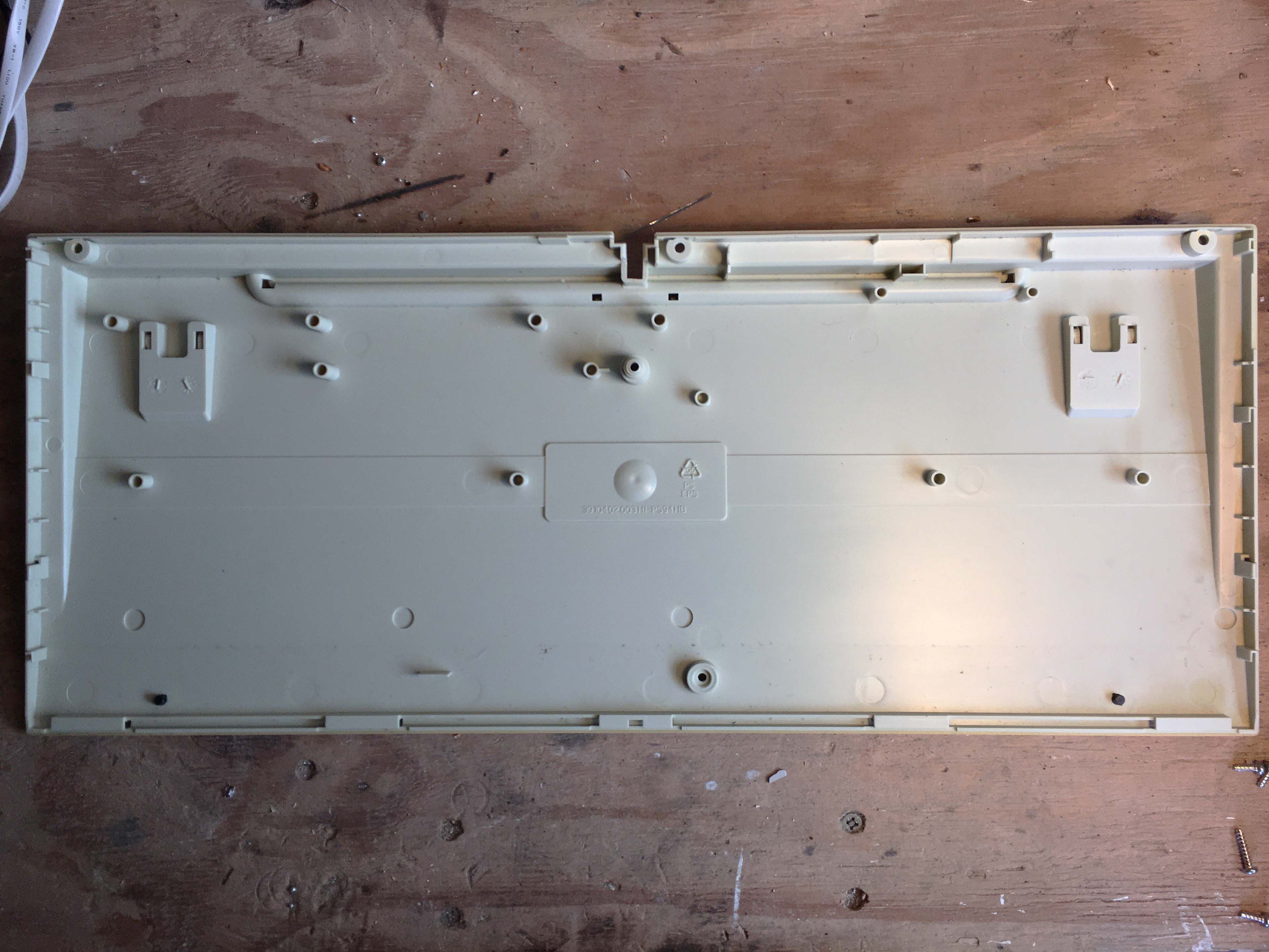 Photo of solid bottom plastic cover of the keyboard that has mounting pegs.