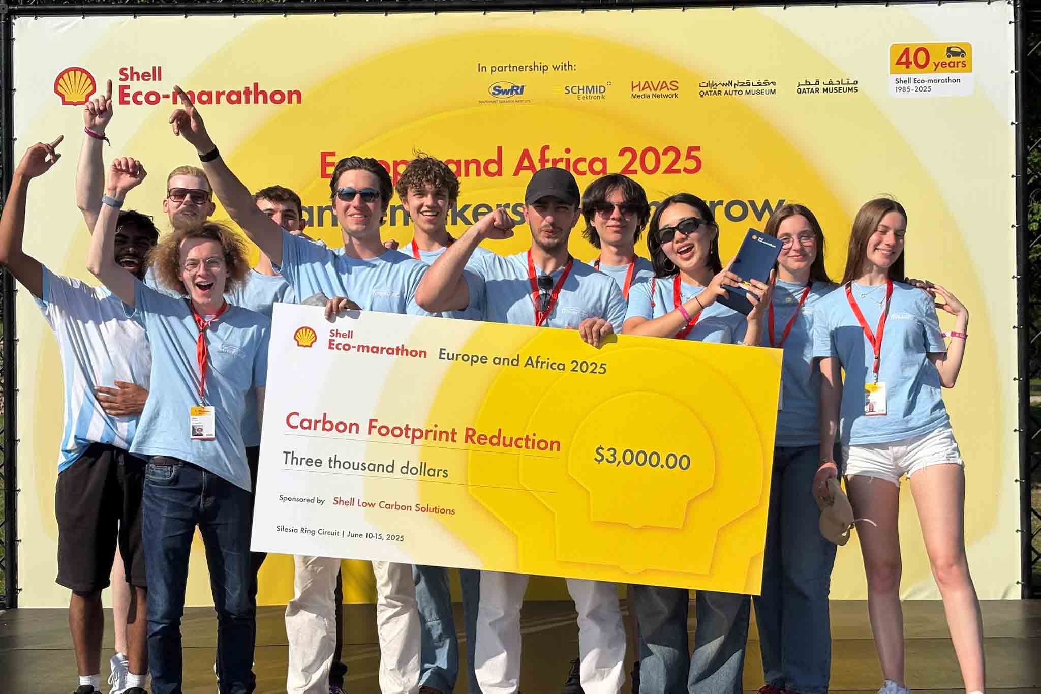 Photo of (most of) 2025 team holding comedy cheque for 1st in Carbon Footprint Reduction award.